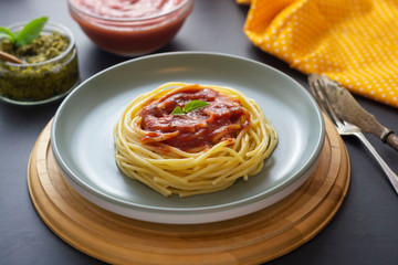 Spaghetti pasta with tomatoes sauce and basil in plate on dark background. Pasta plate isolated.
