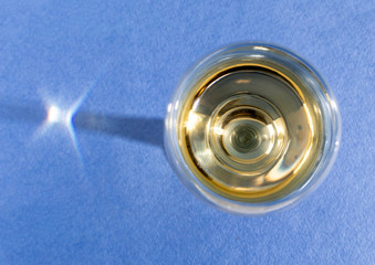 Glass of dry white wine on a blue background top view. Wine from white grapes. Alcohol drink.