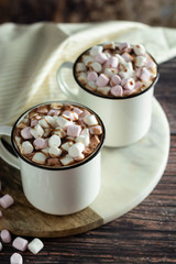 Two cups of hot chocolate, cocoa or warm drink with marshmallows on dark background
