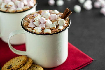 Two cups of hot chocolate, cocoa or warm drink with marshmallows and sweet cookies on dark background
