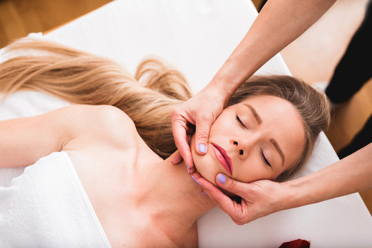 Beautiful woman doing facial massage in a spa salon.