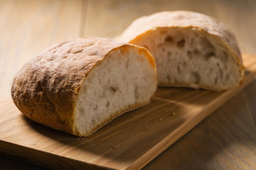 fresh ciabatta cut in halves on wood board