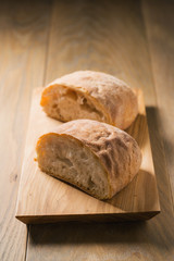 fresh ciabatta cut in halves on wood board