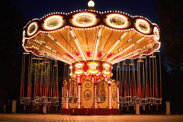 Illuminated swing chain carousel in amusement park at the night - obrazy, fototapety, plakaty