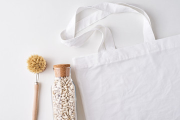 Fototapeta na wymiar Glass jar, wooden brush and shopping bag on a white background. Zero waste concept. Kitchen background with no plastic utensils