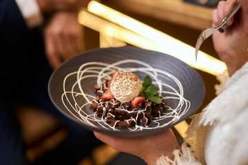 High european cuisine. People eat sweet dessert from beautiful dish and enjoy
