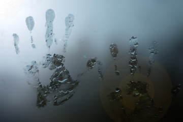 handprints on foggy glass with raindrops