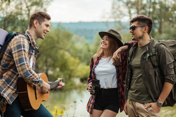 young cheerful couple enjoying listening to their friend's playing the guitar, happiness, friendship, free time, spare time, lifestyle