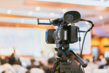 Tv OB camera in a concert or conference hall.Video cameras operator working with his equipment, Cameraman in a meeting room, light Bokeh in Background, selective focus.Vintage filtered photo process.