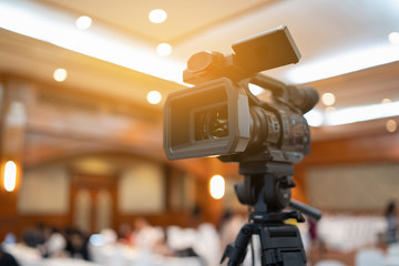 Tv OB camera in a concert or conference hall.Video cameras operator working with his equipment, Cameraman in a meeting room, light Bokeh in Background, selective focus.Vintage filtered photo process.