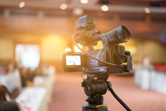 Tv OB camera in a concert or conference hall.Video cameras operator working with his equipment, Cameraman in a meeting room, light Bokeh in Background, selective focus.Vintage filtered photo process.