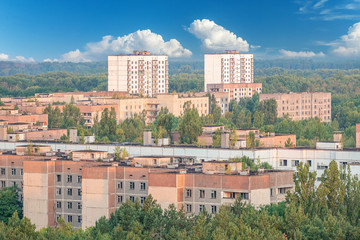 Fototapeta premium aerial view of the lost city of Pripyat wiht blue sky and clouds. a lot of empty concrete floors overgrown with trees. Pripyat is empty after the evacuation for 33 years after the accident 