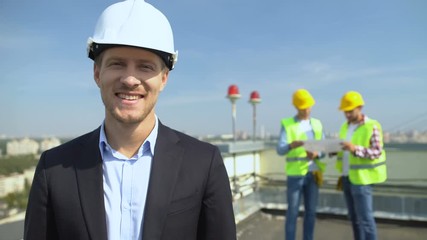 Smiling construction engineer in safety helmet looking camera, skilled architect