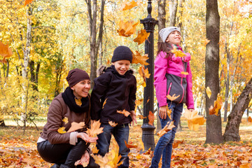 happy family playing with fallen leaves in autumn park