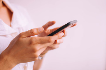 A close-up view of a young woman holding a smartphone on a white background