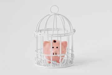 Piggy bank closed in a cage on white background - Concept of savings blocked