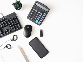 top view of office desk table with  calculator, notebook, plastic plant, smartphone and keyboard on white background, graphic designer, Creative Designer concept.