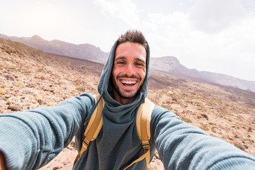 A caucasian young traveller takes a selfie photo hiking a volcano on a canary island.