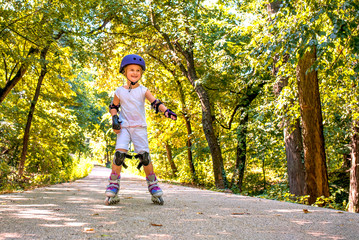 Beautiful little girl enjoying inline roller skating in autumn park