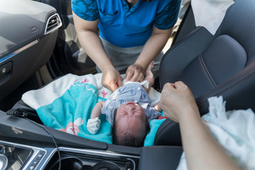 father changing diaper to crying baby in car