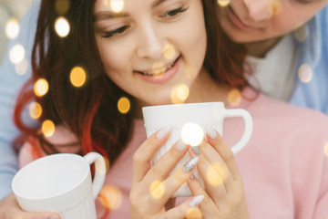 Young happy couple in love in the morning in bed with cups of coffee having Breakfast.