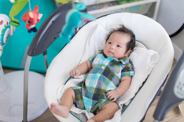 Cute baby laying in bouncer chair and looking mobile