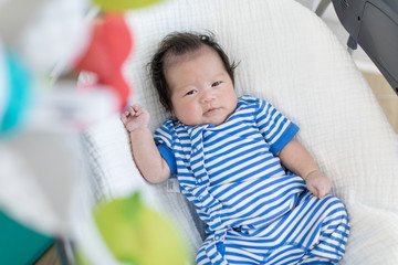 Cute baby laying in bouncer chair and looking mobile