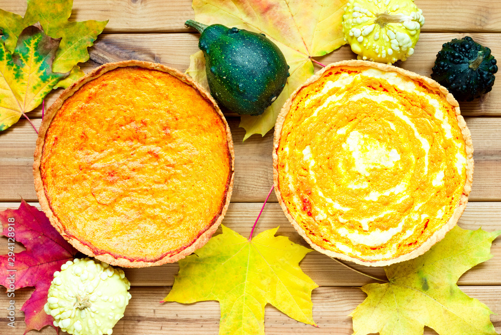 Wall mural two pumpkin pies on a wooden table decorated with maple leaves and small warty pumpkins. homemade ba