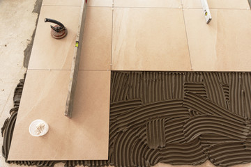 Construction repairs in a room on laying of a ceramic tile on a concrete floor with use of the specialized tool and glue mixes