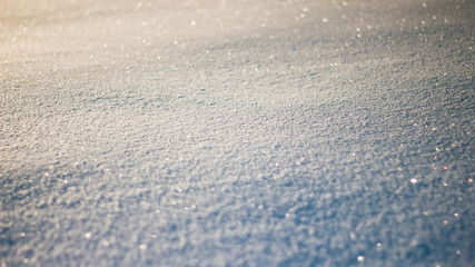 Snowy white background. The texture of the snow. Shiny snow with bokeh and blurred background close-up. White snow-covered field. Macro photo of snow.