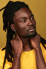 pensive thoughtful male model with new hairstyle touching his neck looking aside, close up photo. isolated yellow background