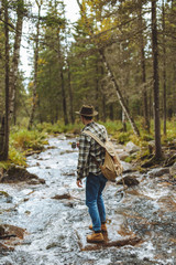 tourist wearing hat, backpackm jeansm checked shirt enjoying cold water, back view full length photo, travel, pastime