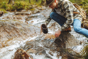 young man is taking water from river, close up cropped side view photo