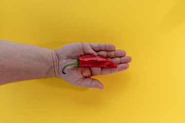 Fototapeta premium Piments et main sur fond de couleur jaune