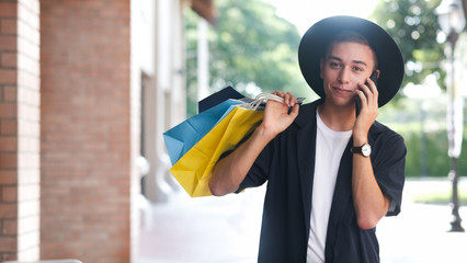 Young man with shopping bags is using a mobile phone while doing shopping
