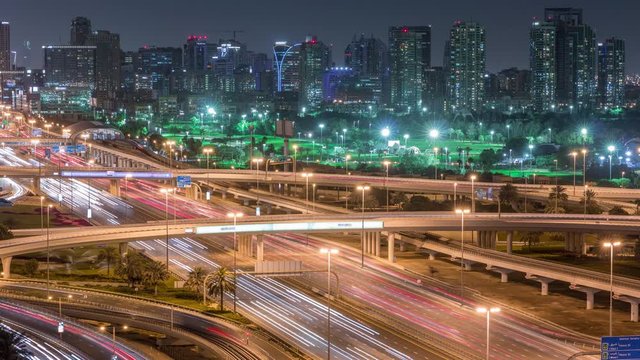 Dubai Golf Course with a cityscape of Gereens and tecom districts at the background aerial night timelapse. Traffic on sheikh zayed road with junction