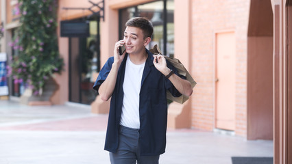 Young man with shopping bags is using a mobile phone while doing shopping