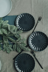 Christmas / New Year composition. Festive christmas / Thanksgiving table decorated with fir branches, garland,  plates, knifes, forks. Flat lay, top view. Winter holidays concept.