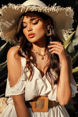 beautiful woman with dark hair in elegant dress posing in summer garden