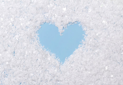 White fluffy artificial snow on blue background with heart