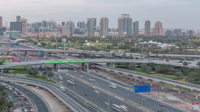 Dubai Golf Course with a cityscape of Gereens and tecom districts at the background aerial day to night transition timelapse. Traffic on sheikh zayed road with junction
