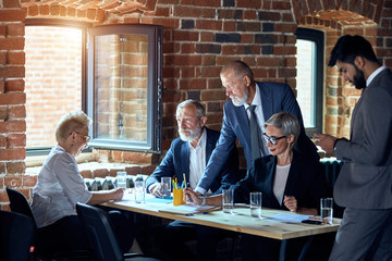 Five businessmen work in office at table,discuss and take notes. The window open, brick wall.