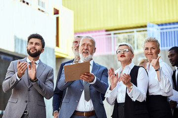 Group of businessmen wear stylish suits in the street give an assessment and clap