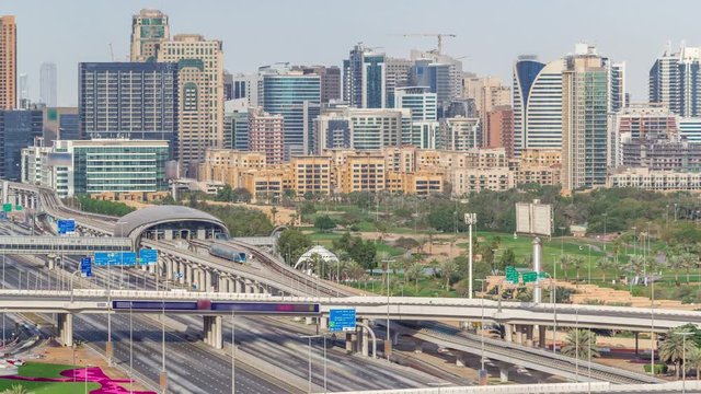 Dubai Golf Course with a cityscape of Gereens and tecom districts at the background aerial timelapse. Traffic on sheikh zayed road with junction and metro starion
