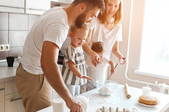 young cheerful couple and their kids trying to cook cake. close up side view photo