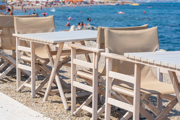 Empty table and chairs in restaurant, Greece. Beach cafe near sea, outdoors. Travel and vacation concept