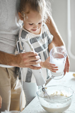 man is working with blender while his kid holding a jar of water. close up cropped photo