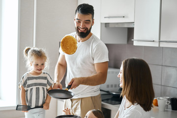 bearded happy father showing tricks with pancakes in the kitchen, close up photo. - Powered by Adobe