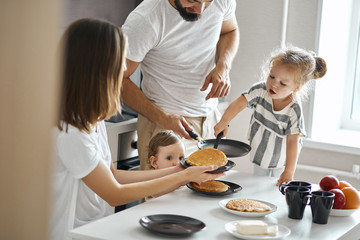 hardworking young girl helping her parents to cook pancakes. close up photo