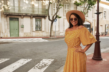 Young pretty woman outdoor portrait. Stylish girl in yellow polka dot dress, sunglasses and thatch...